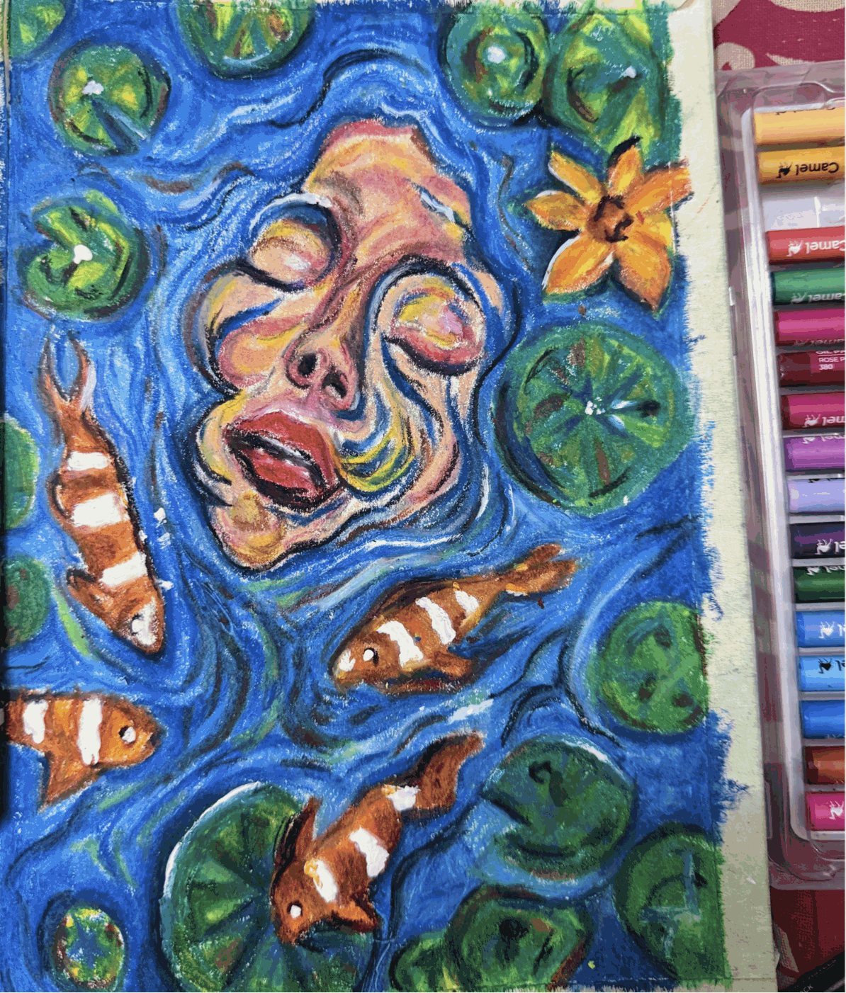 White poster color on the koi stripes and eyes, the lily pads and the ripples, with the oil pastel box beside the page